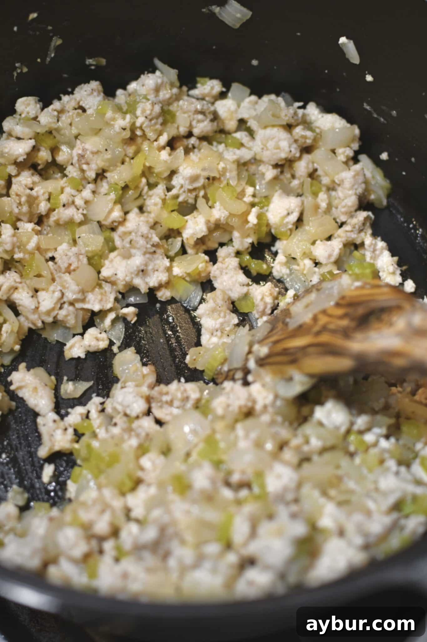The buffalo sauce being added to the cooked chicken and vegetables, creating a vibrant base.
