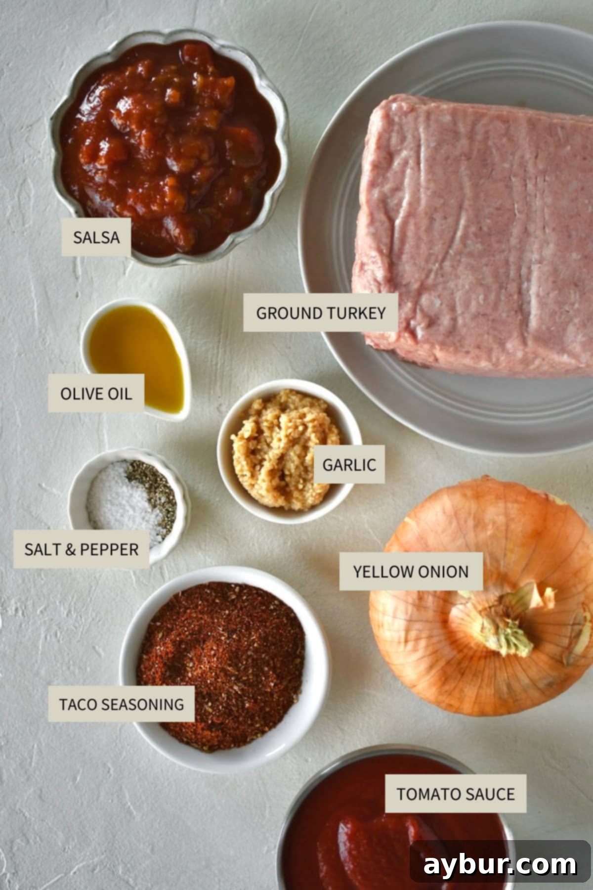 Fresh ingredients laid out for making Ground Turkey Tacos, including ground turkey, onions, garlic, tomato sauce, and salsa.