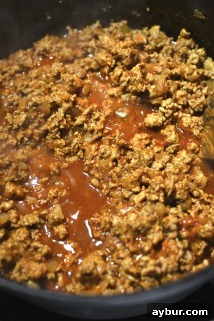 The ground turkey taco mixture simmering gently on the stovetop, allowing flavors to deepen and sauce to thicken.