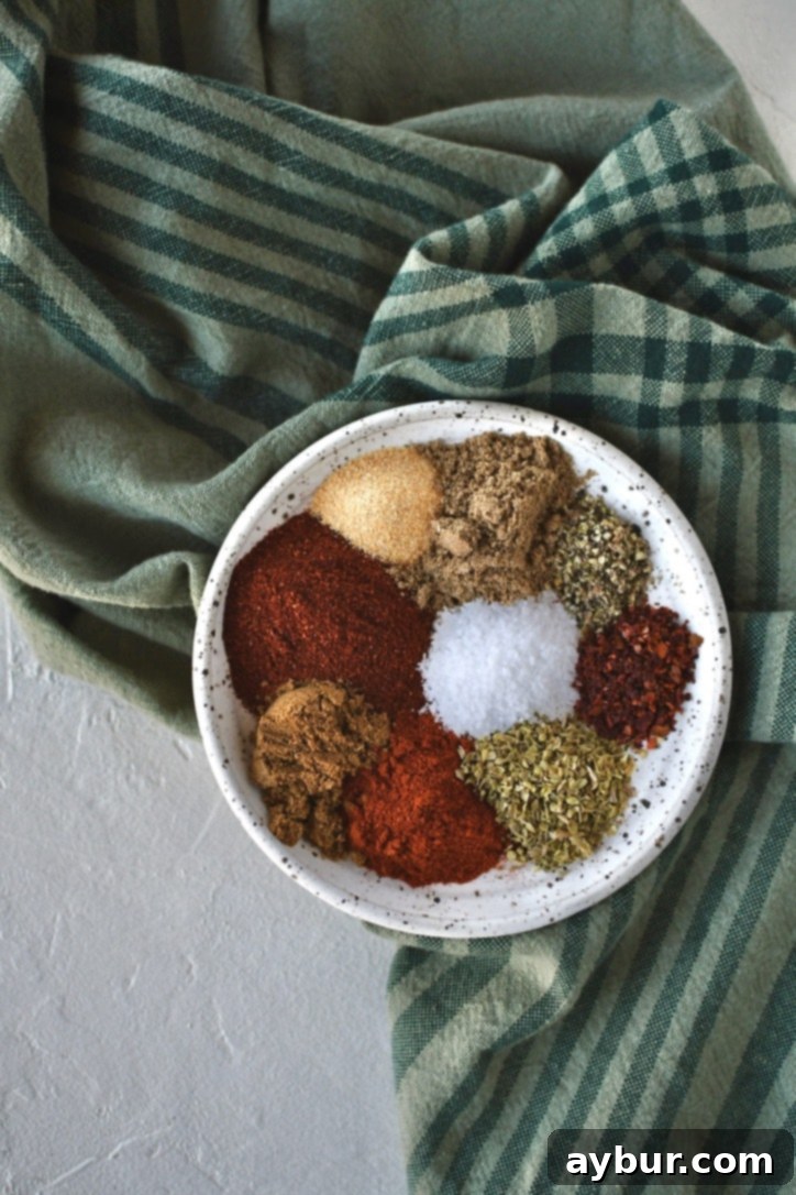 DIY Taco Spice Blend 4 A selection of individual spice piles arranged on a white plate, including various chili powders, cumin, and garlic, ready to be combined for homemade taco seasoning.