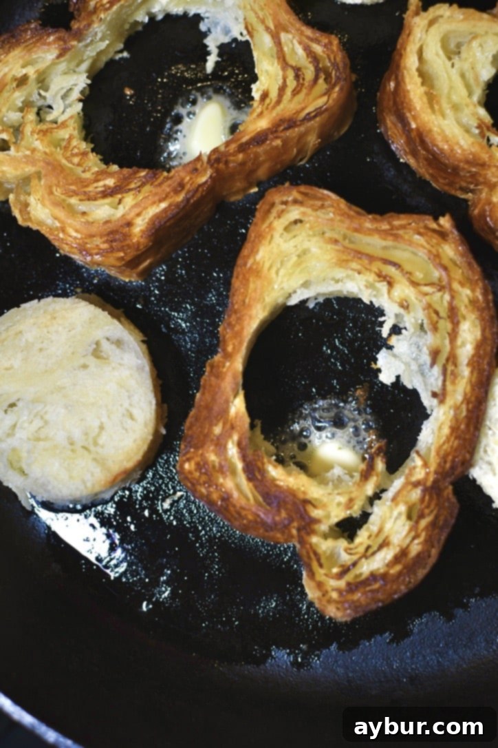 Flipped toast exposing the buttered side that is golden brown. Adding a little piece of butter into the hole.
