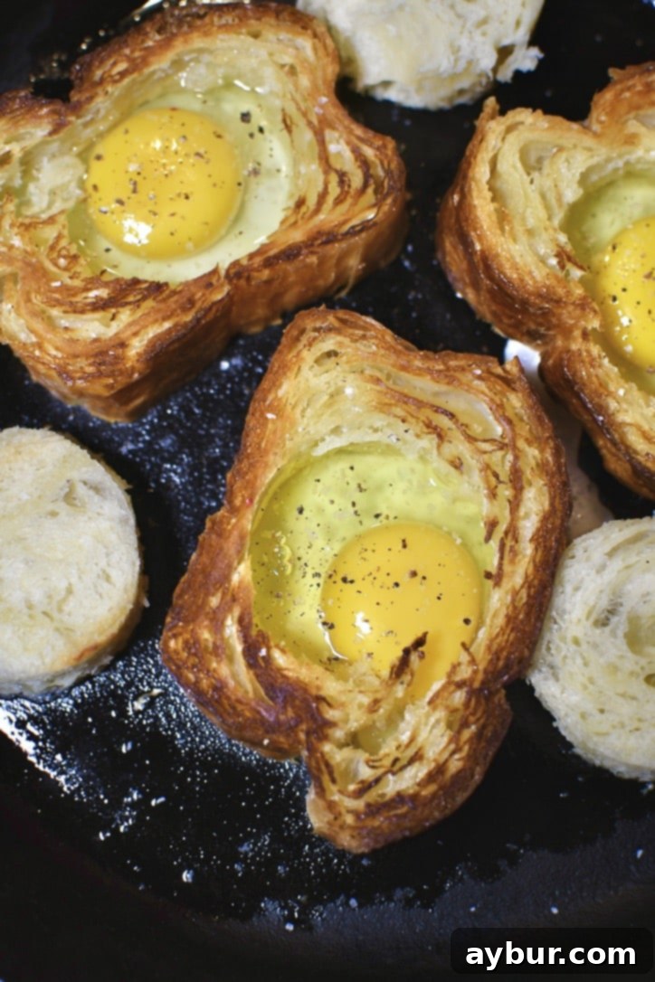 Cracked egg in the hole of the toasted bread.