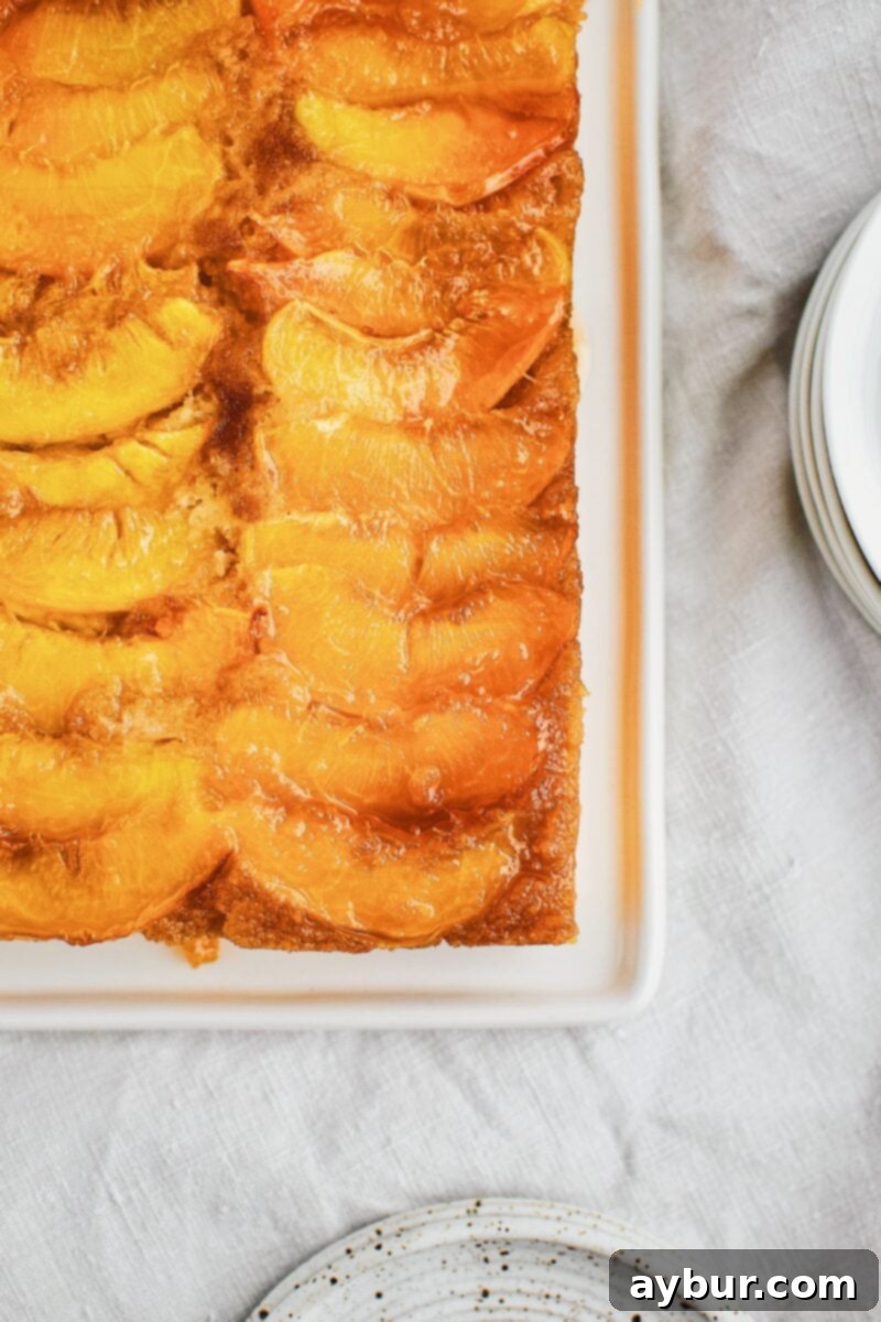 Close-up of the golden-brown caramelized peach topping of an Upside-Down Cake, showing the glistening fruit.