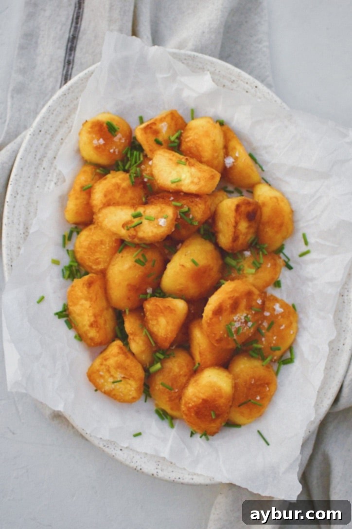 Addictively Crispy Roasted Potatoes 9 Crispy Roasted Potatoes served on a white platter, garnished with flaky sea salt and freshly chopped chives, ready to be enjoyed.