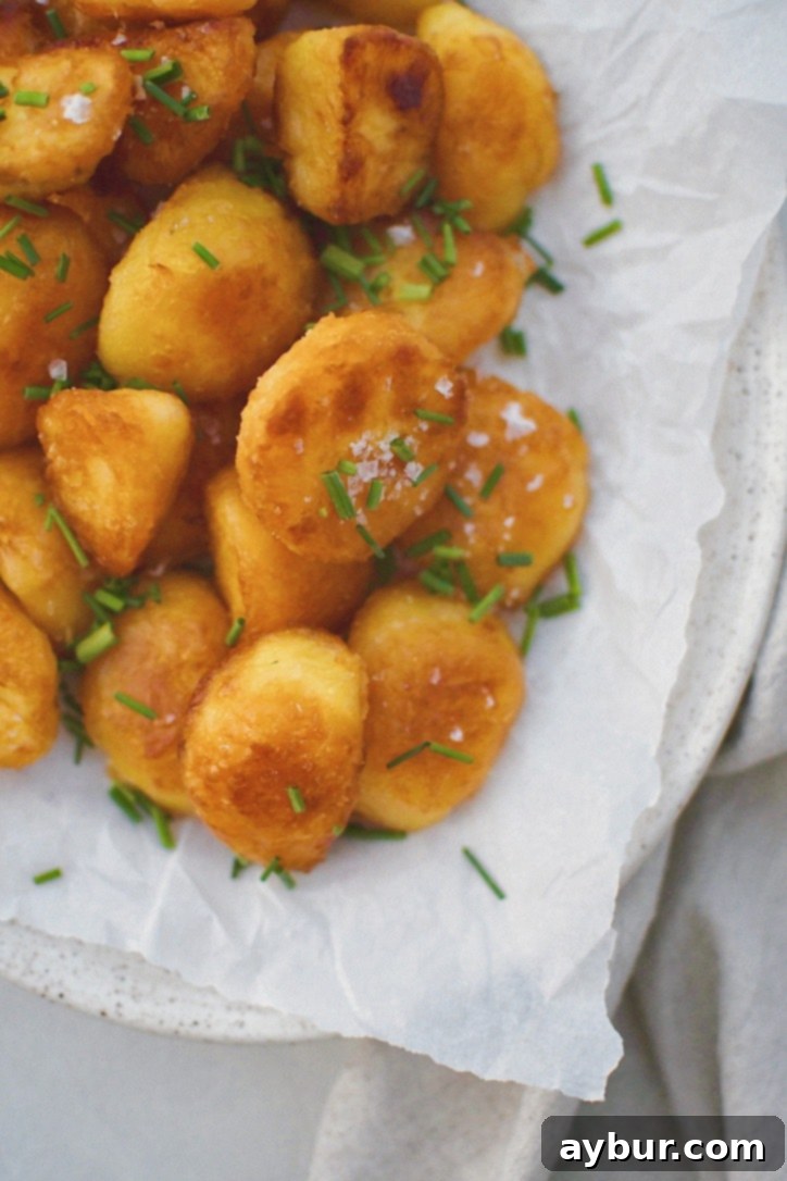 Addictively Crispy Roasted Potatoes 10 Crispy Roasted Potatoes on a platter with more flaky sea salt and chopped chives, emphasizing their deliciousness.