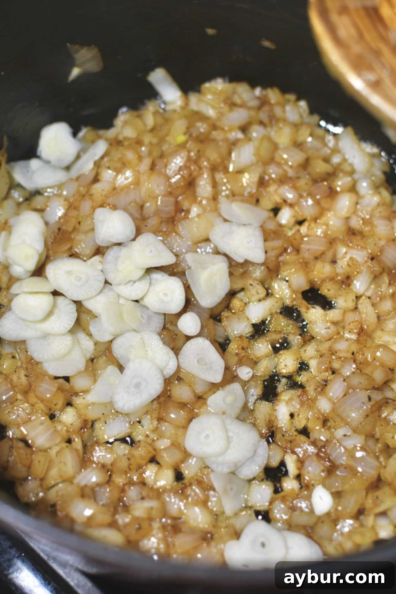 Onions cooked in bacon fat and butter, adding sliced garlic to the pan.