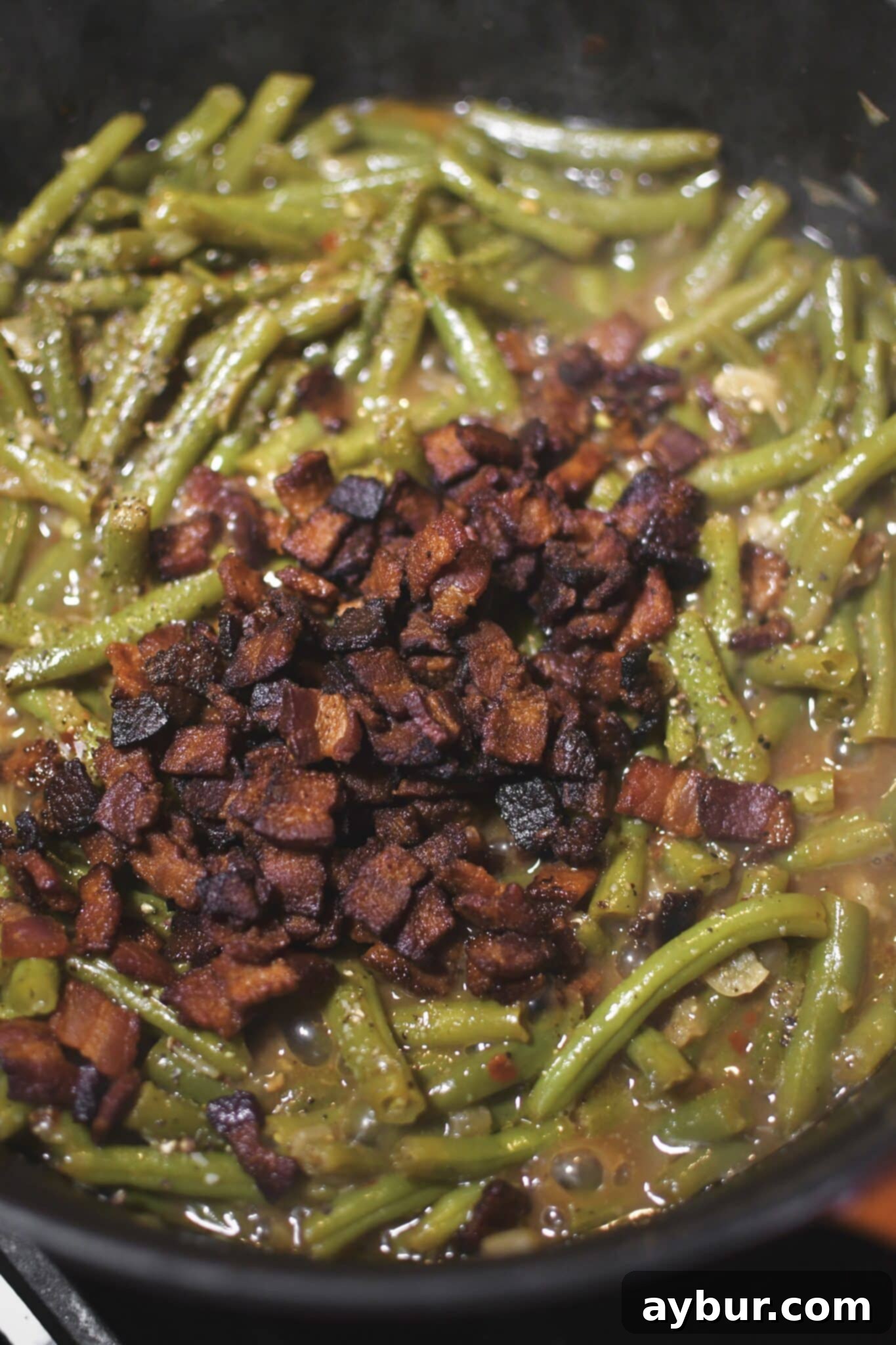 Beans after simmering in a large pot for 40 minutes. Adding the crispy bacon back to the pot.