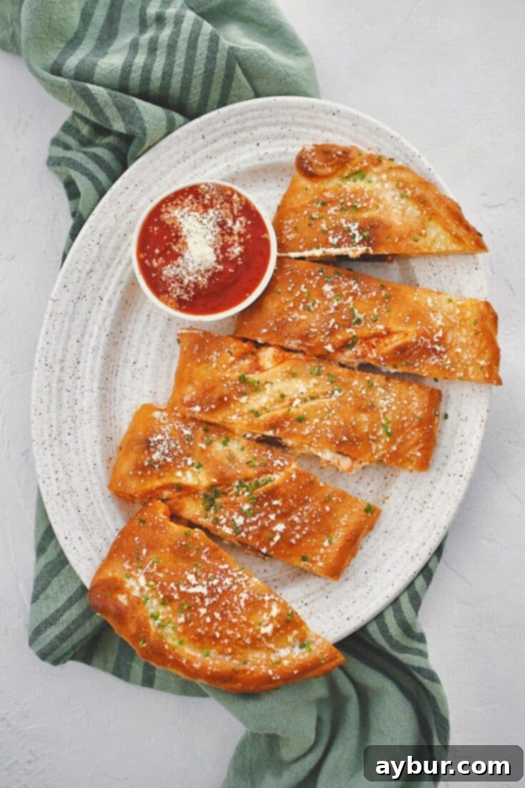 Calzone fresh out of the oven, brushed with garlic butter, and dusted with grated parmesan and chives and sliced. Served with a side of marinara sauce.