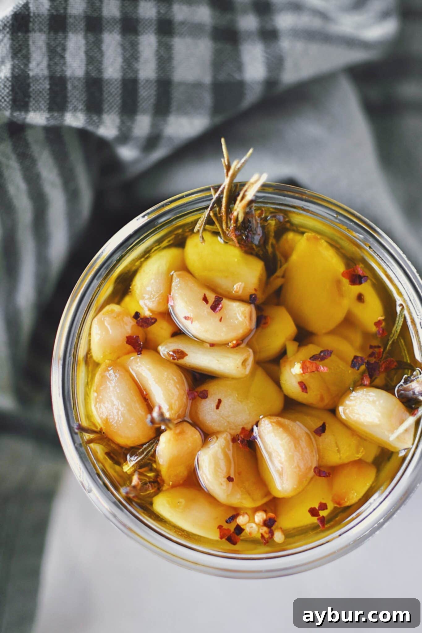 Velvety Garlic Confit 2 A glass jar filled with golden confit garlic cloves submerged in olive oil, ready for use.