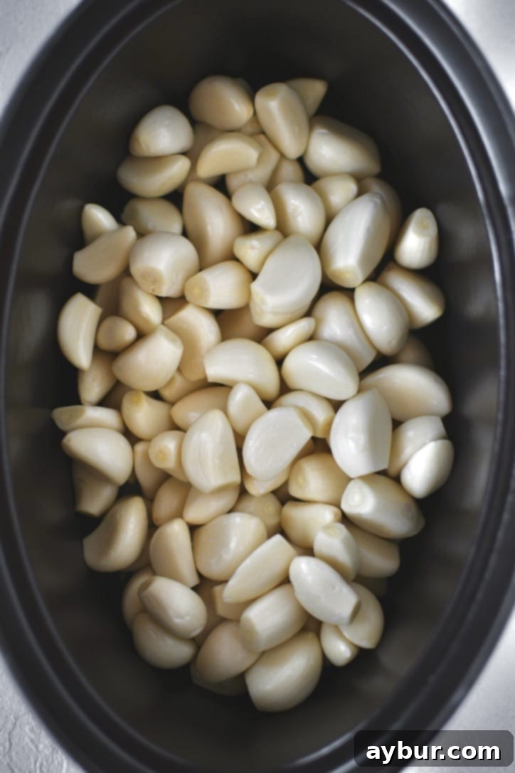 Velvety Garlic Confit 6 Garlic cloves arranged in a cast iron pot before the addition of olive oil and herbs.