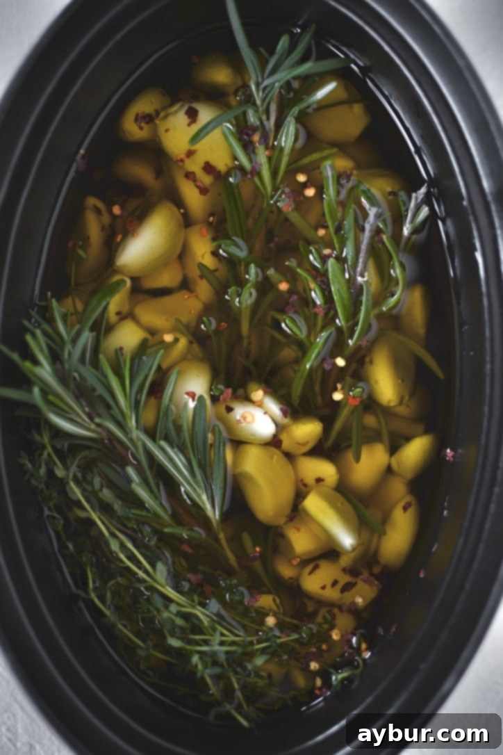 Velvety Garlic Confit 7 Garlic cloves in a cast iron pot, now covered with olive oil and sprigs of fresh herbs, ready for the oven.