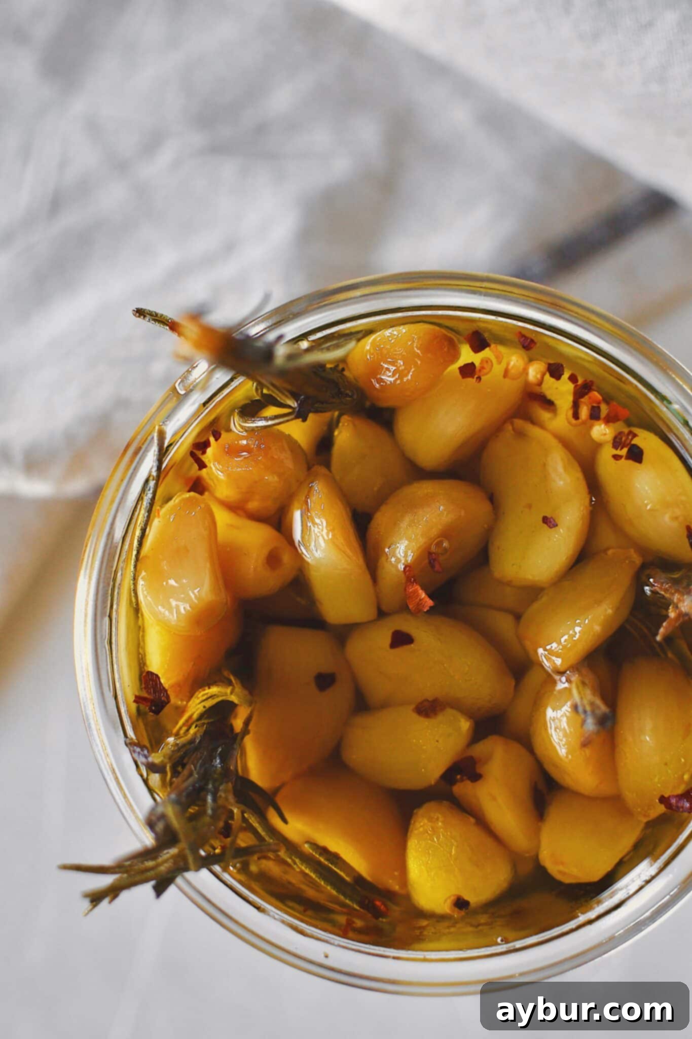 Velvety Garlic Confit 9 Confit garlic stored in a glass jar, fully submerged in its aromatic olive oil, ready for refrigeration.