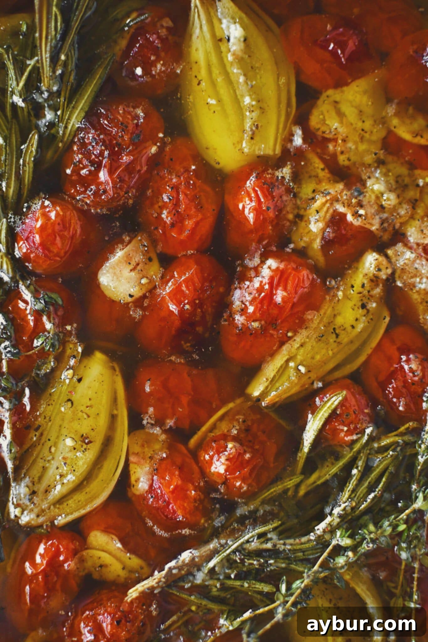 Slow-Roasted Tomato Confit 2 Grape tomatoes in a pan with shallots, sliced garlic, thyme, rosemary, salt, and pepper after roasting and made into confit.
