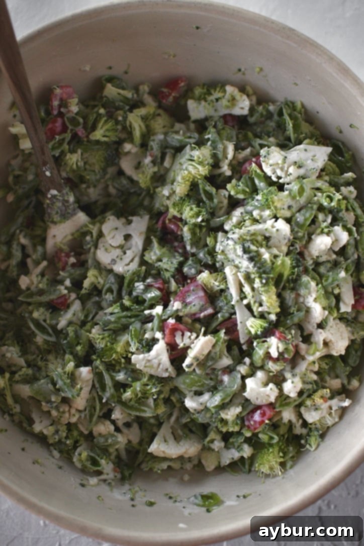 Crisp Snap Pea Salad 5 Colorful mix of snap peas, broccoli, cauliflower, and tomatoes tossed lightly with dressing in a large bowl.