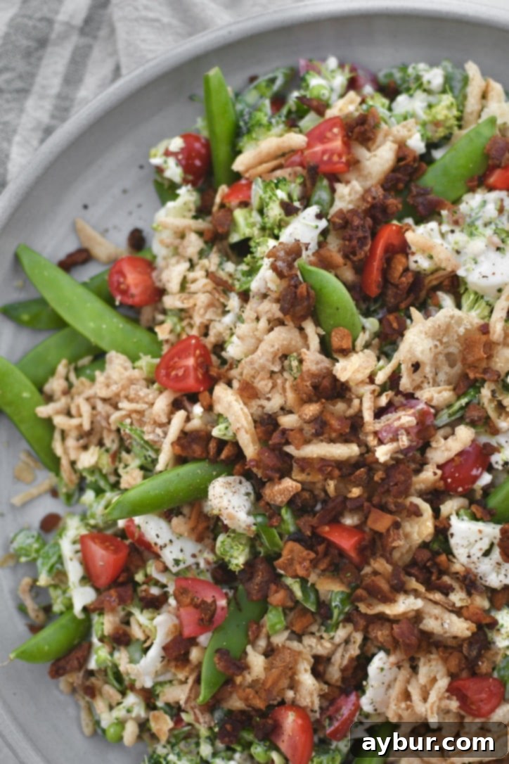 Crisp Snap Pea Salad 8 Beautifully presented Snap Pea Salad on a serving platter, adorned with extra crispy onions and bacon, perfect for any gathering.