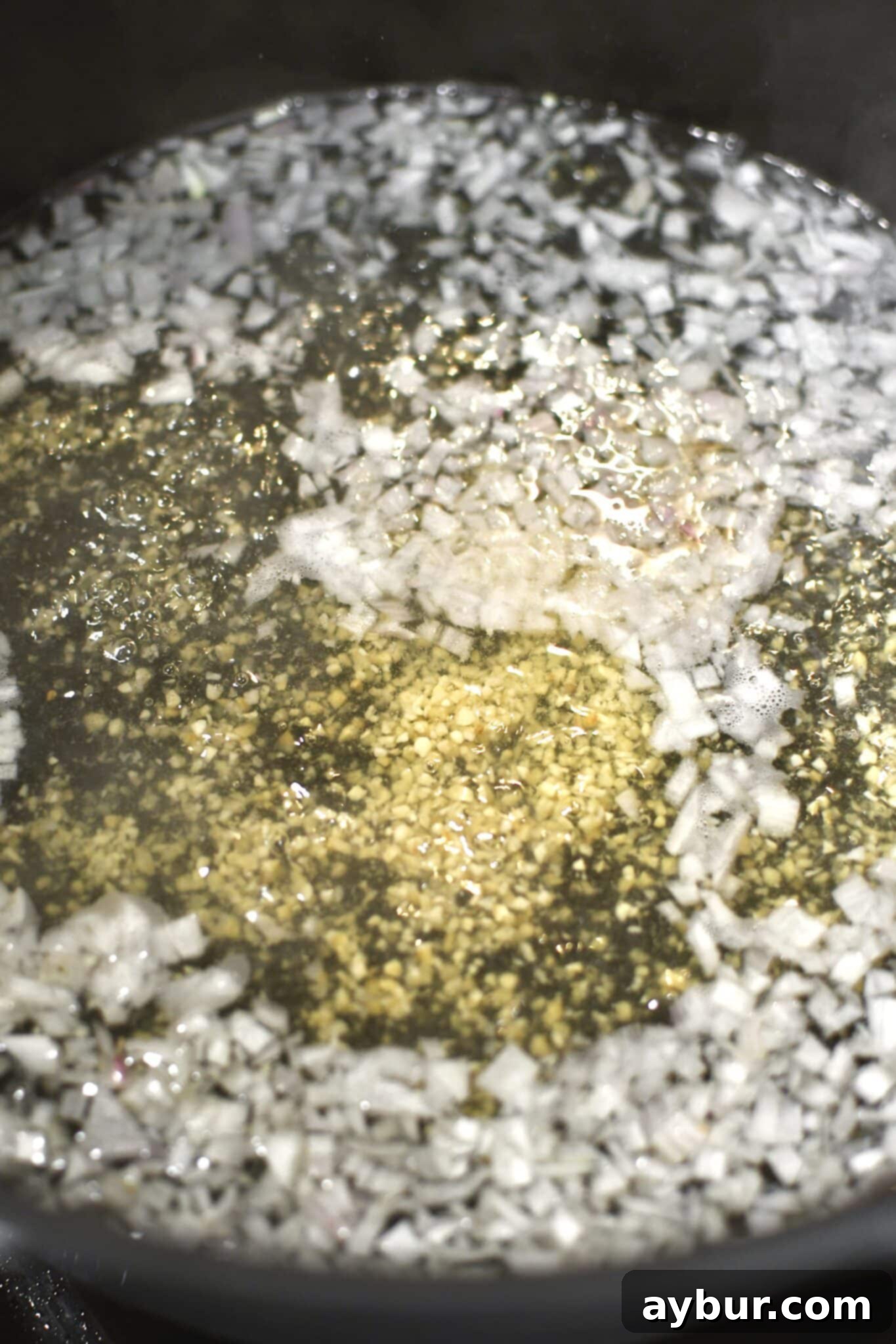 Wine, garlic, and shallots cooking in a large pot.