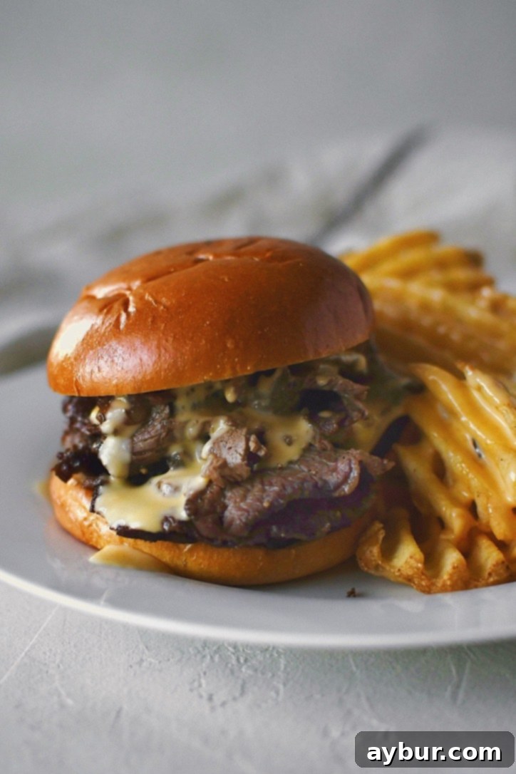 A warm, inviting roast beef sandwich generously topped with a rich cheddar cheese sauce, served alongside crispy waffle fries for a satisfying meal.