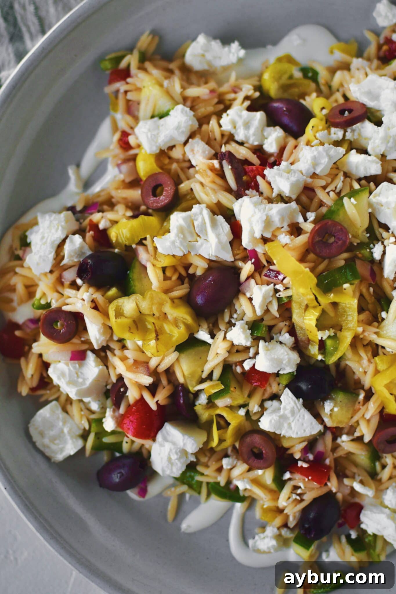 Platter of Easy Greek Pasta Salad, generously topped with crumbled feta cheese, ready to be served and enjoyed by guests.