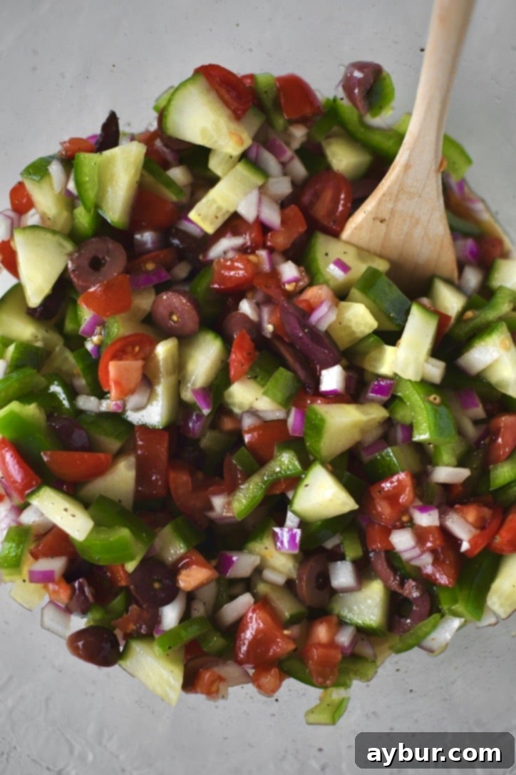 A large bowl containing a thoroughly mixed combination of chopped vegetables, olive oil, red wine vinegar, and seasonings, allowing the flavors to meld.