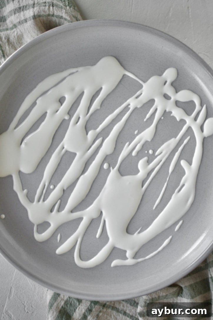 A serving platter with a layer of drizzled whipped feta dip at the bottom, creating a creamy base before the Greek Pasta Salad is added.