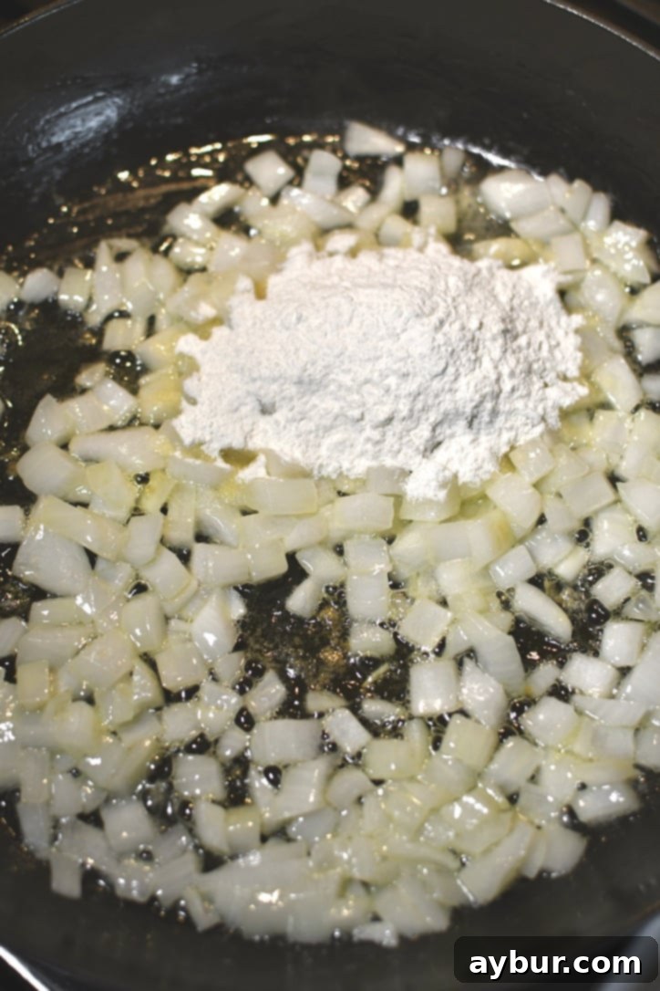 Sautéing diced yellow onions in melted butter for the creamy chicken filling base.