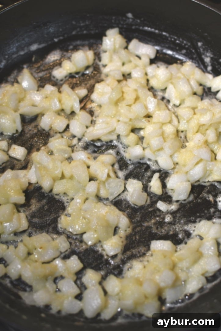 Whisking all-purpose flour into the sautéed onions and butter to form a roux, which thickens the sauce.