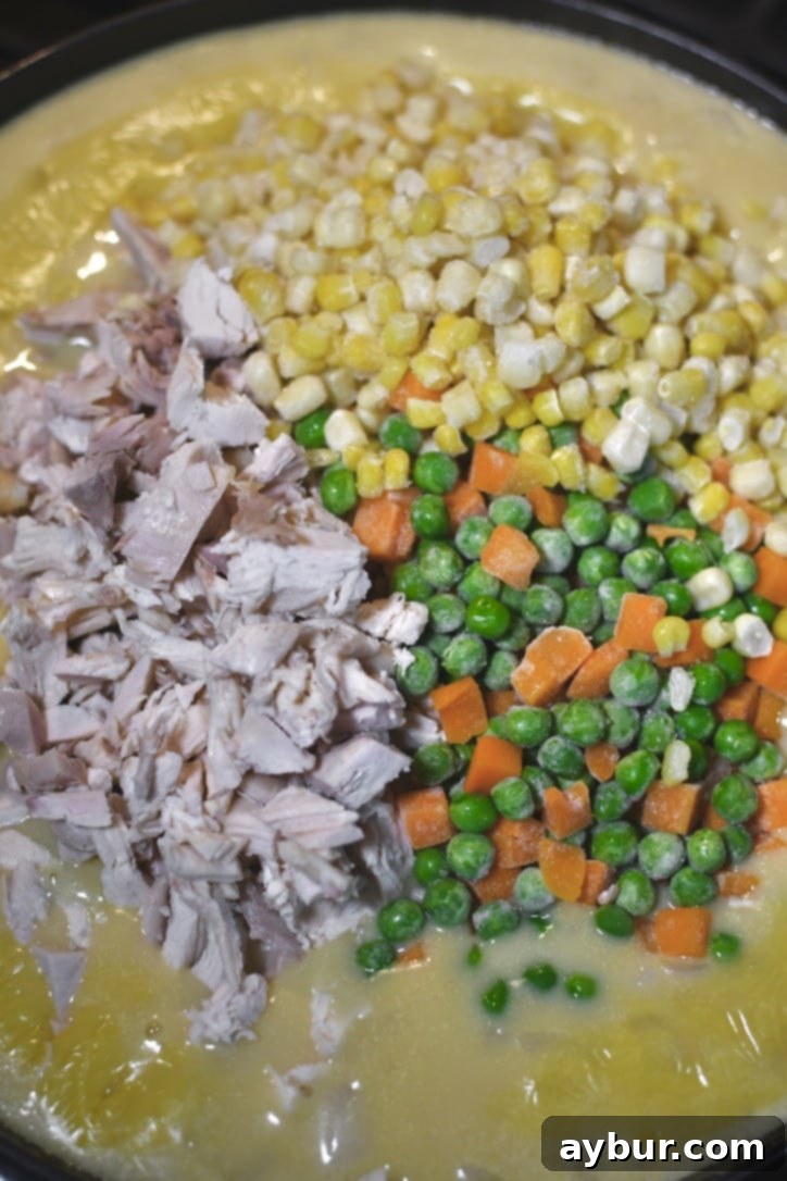 Pouring the creamy chicken and vegetable filling into a greased 9x13-inch baking dish.