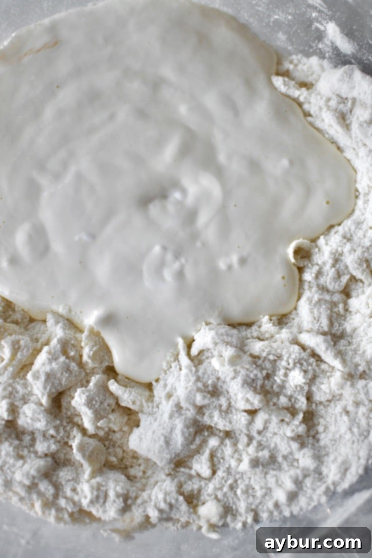 The blended egg and sour cream mixture being added to the dry ingredients and butter.