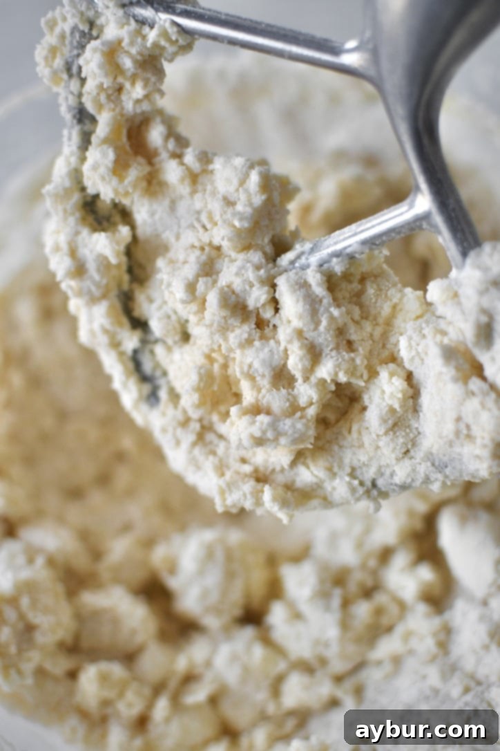 Scone dough beginning to form a shaggy consistency after wet ingredients are added, indicating it's nearly mixed.