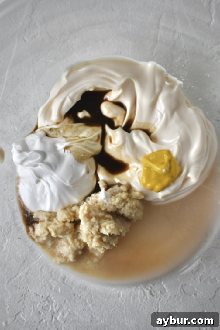All the horseradish cream sauce ingredients neatly arranged in a bowl, ready to be combined with a whisk.