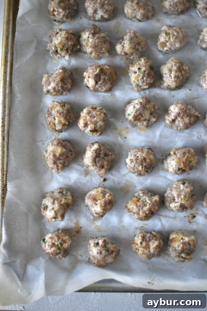 Portioned out meatball mixture into tiny meatballs, on a tray and rolled into uniform balls, baked till set with a slight browning.
