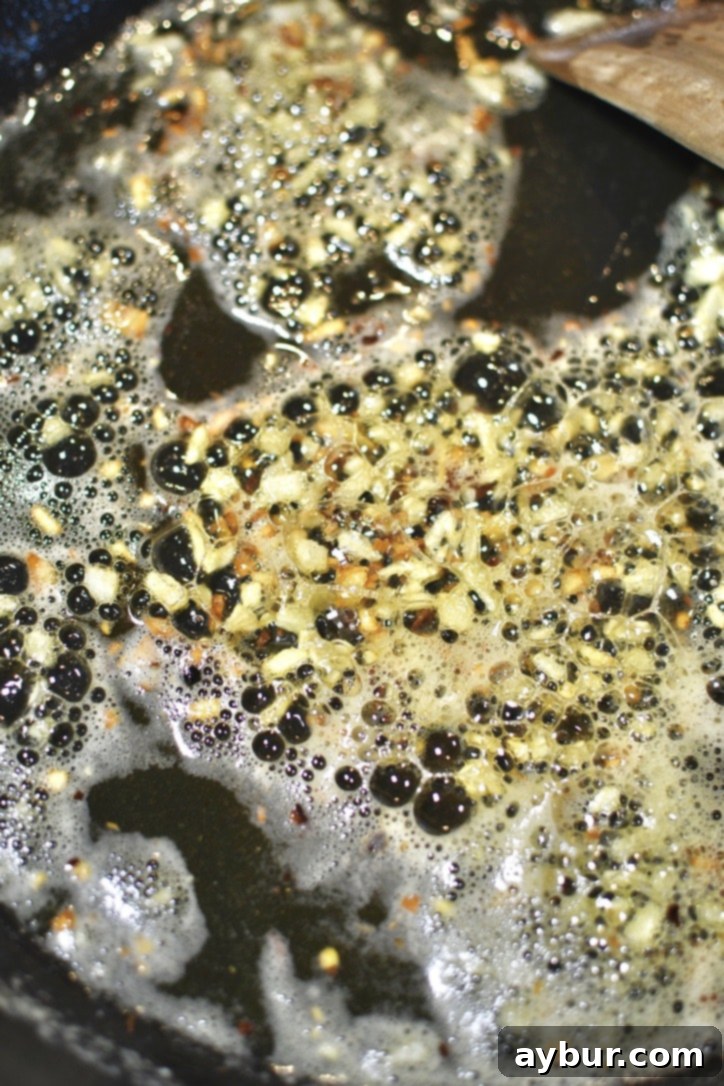 Garlic and red pepper flakes cooking in melted butter and olive oil in a large pan, cooked till lightly browned.