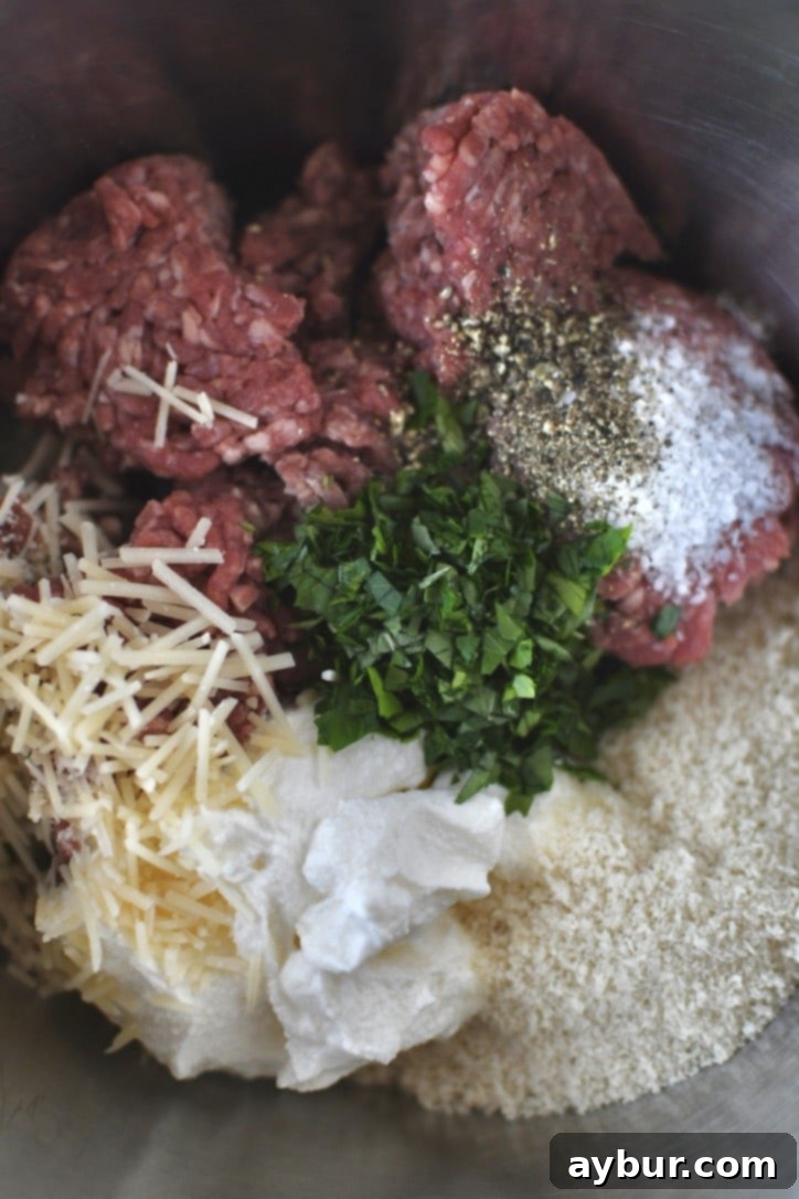 Ground beef and dry ingredients for meatballs in a bowl before adding the cooked onions.