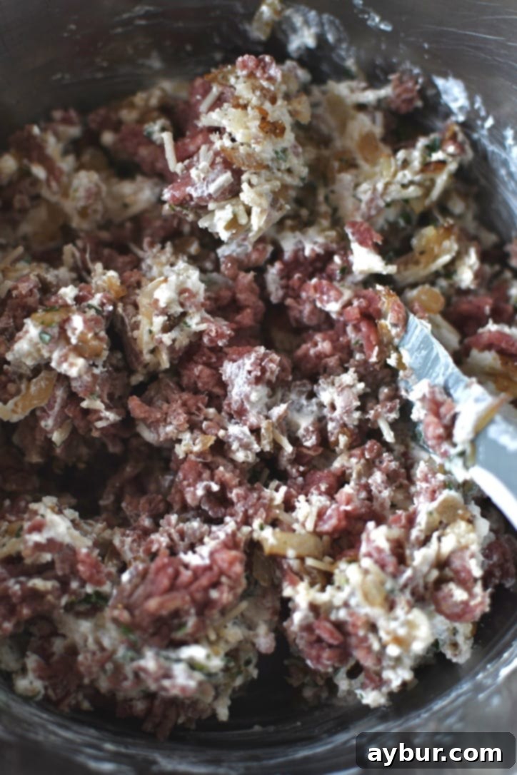Ingredients for meatballs in a bowl halfway through stirring, showing the mixture beginning to combine.