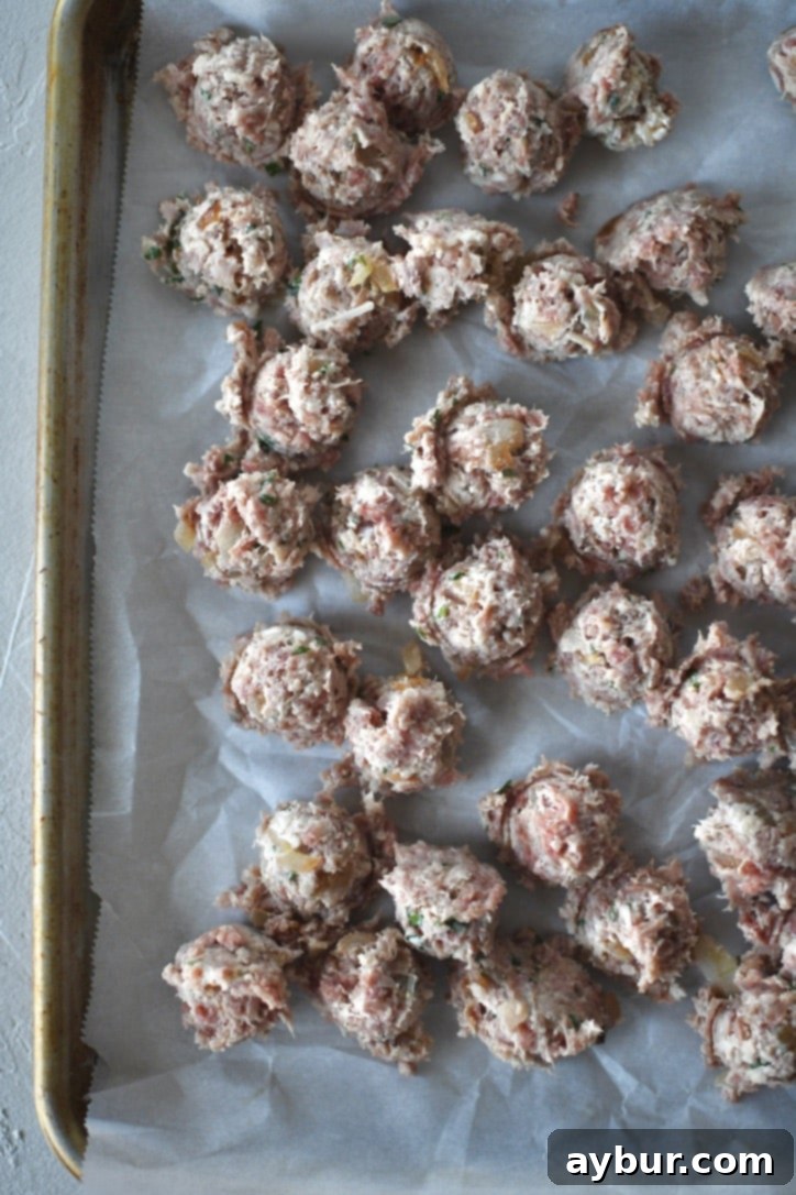 Portioned out meatball mixture into tiny meatballs, neatly arranged on a tray before rolling.