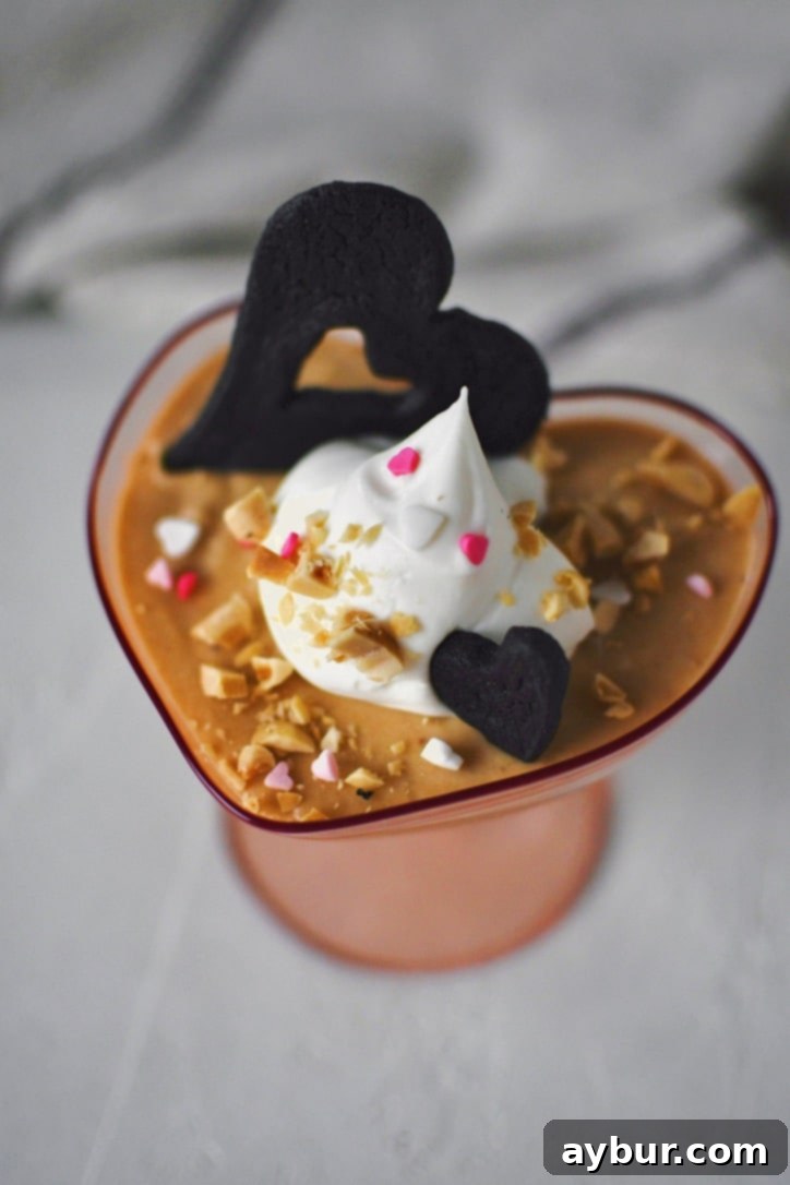 Peanut Butter Mousse in a small heart shaped cup, topped with whipped cream, peanuts, and a chocolate wafer.