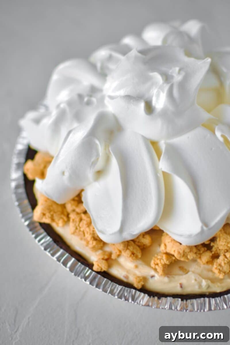 Peanut Butter Paradise Pie 10 The initial stage of finishing the pie, with a generous layer of peanut butter crumble and large dollops of Cool Whip added.