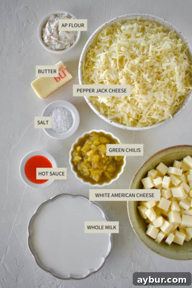 Creamy White Queso 3 A selection of fresh ingredients laid out on a cutting board, including blocks of American cheese and pepper jack, a can of diced green chilis, butter, and milk, all ready for making White Queso Dip.