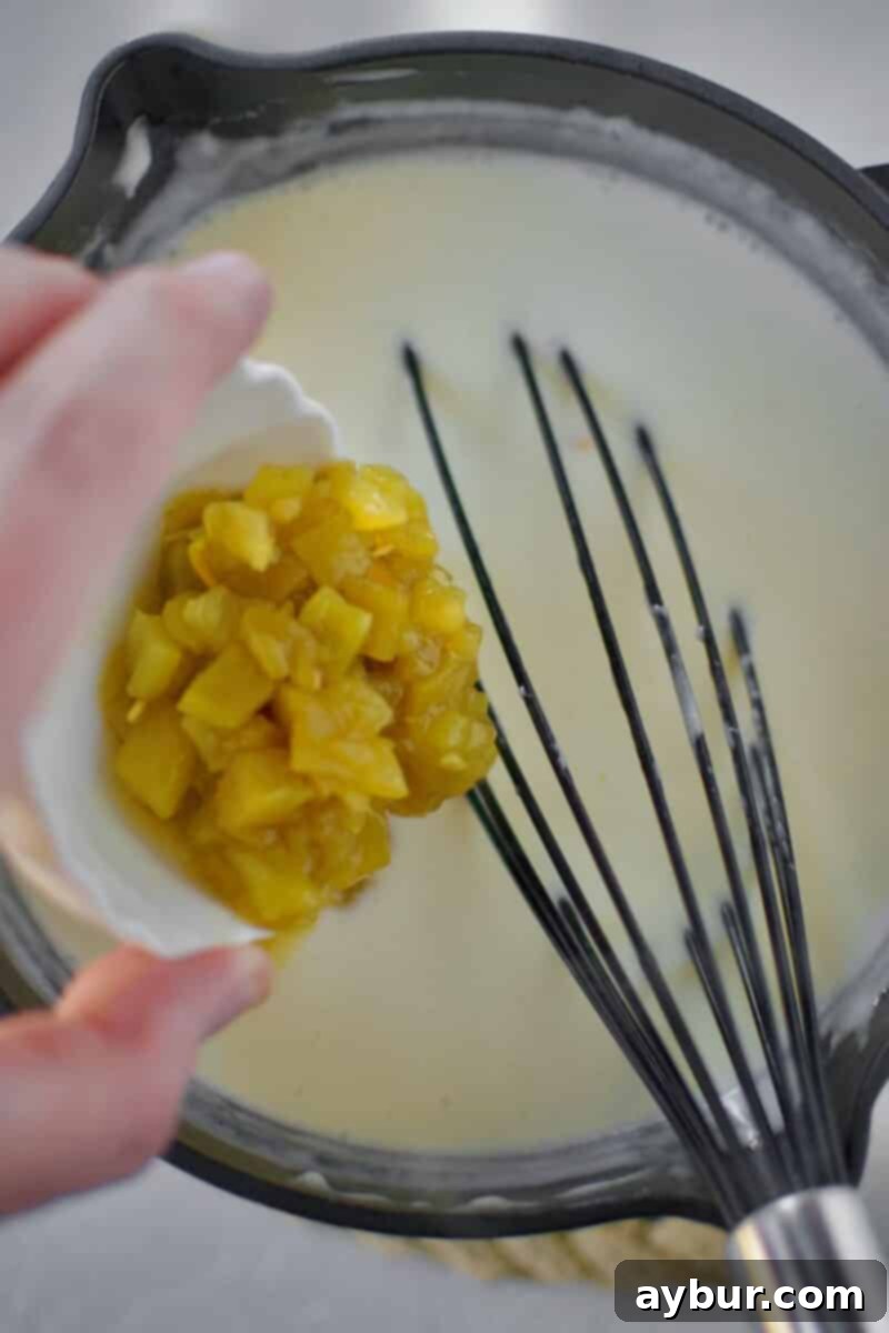 Creamy White Queso 7 The White Queso Dip, now smooth and creamy, with green chilis mixed in, gently simmering in a saucepan, ready to be served.