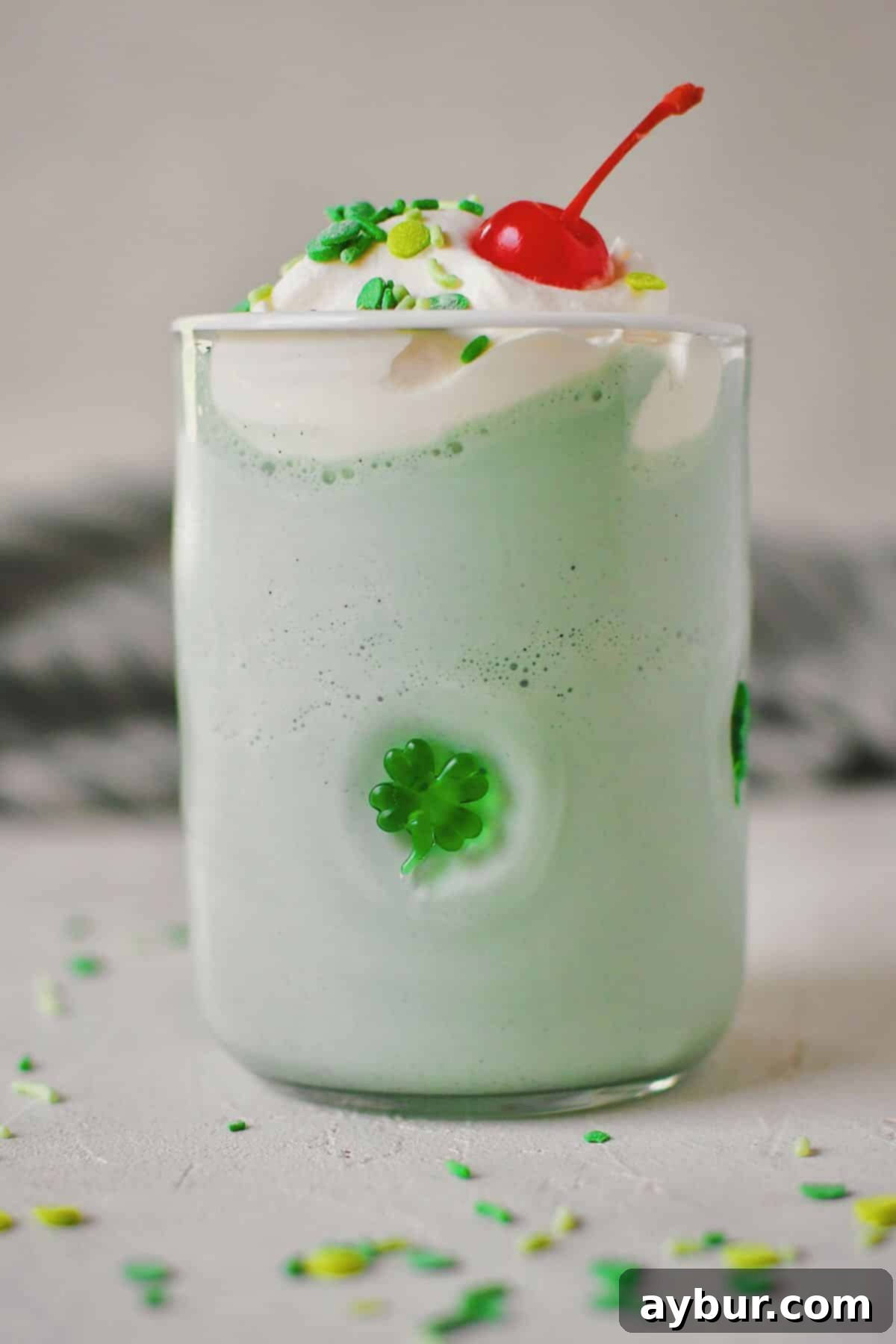 Another enticing shot of the Shamrock Shake, beautifully presented in a shamrock-embellished glass, garnished with whipped cream, colorful sprinkles, and a cherry, capturing its festive spirit.