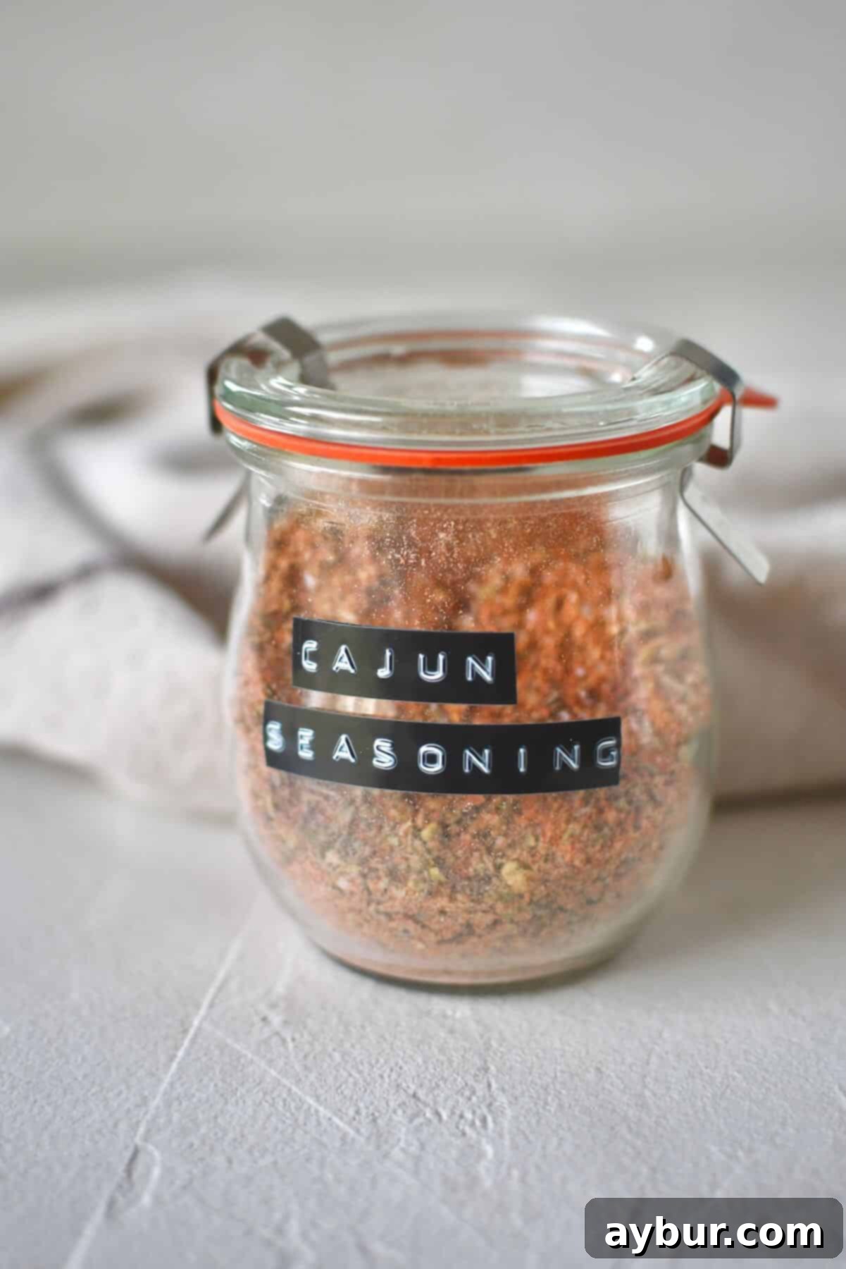 Blended Cajun Seasoning in a jar, with a spoon nearby.