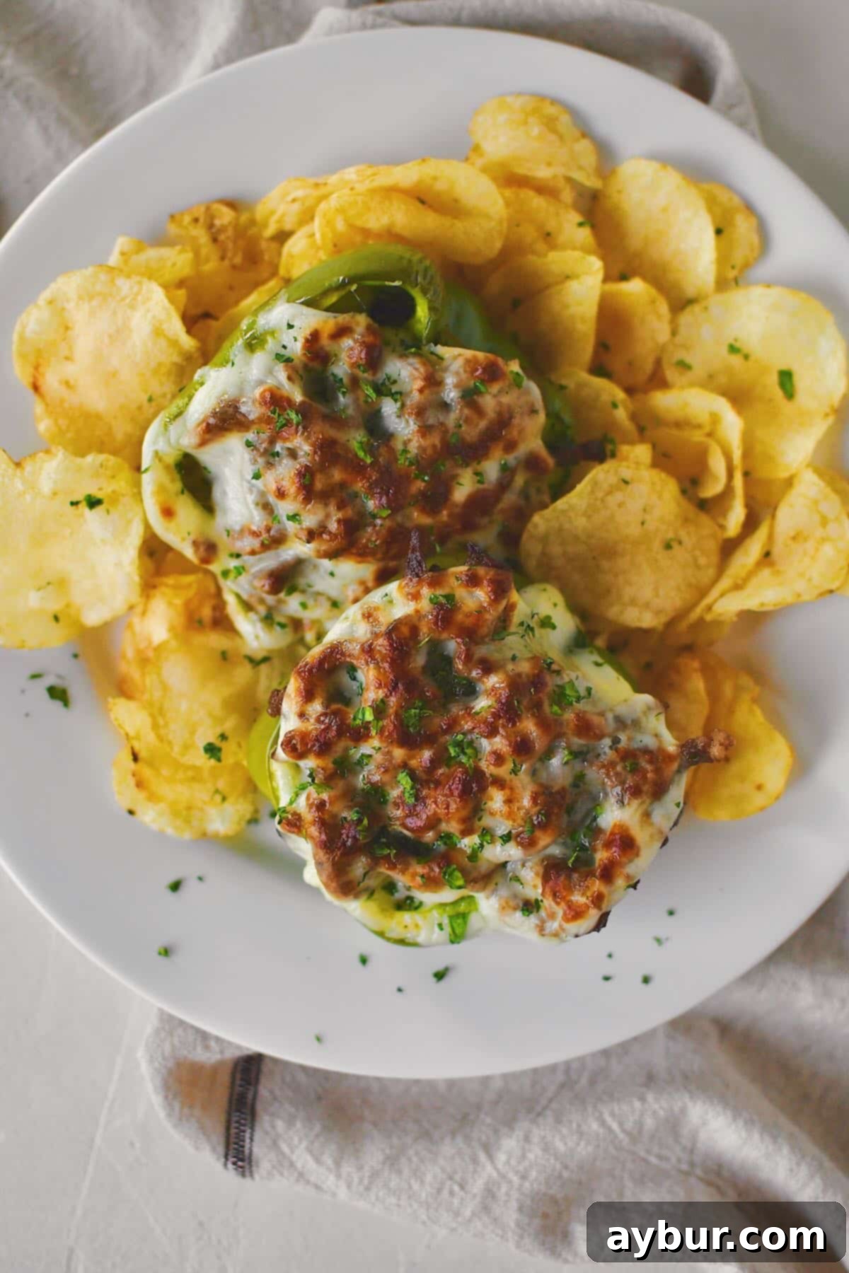 Philly Cheesesteak Stuffed Peppers on a plate ready to eat, served with a side of crunchy potato chips.