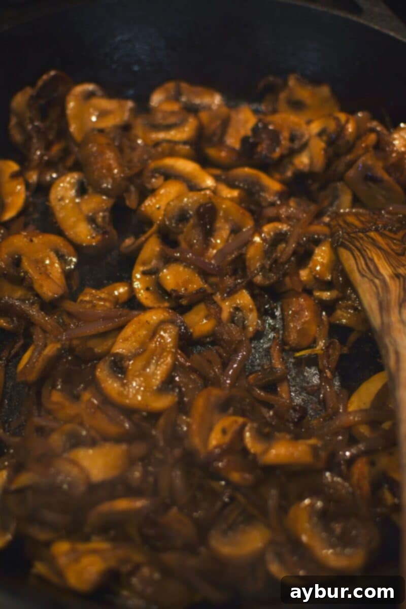 Caramelized onions and browned mushrooms glistening in a skillet, having been cooked to perfection.