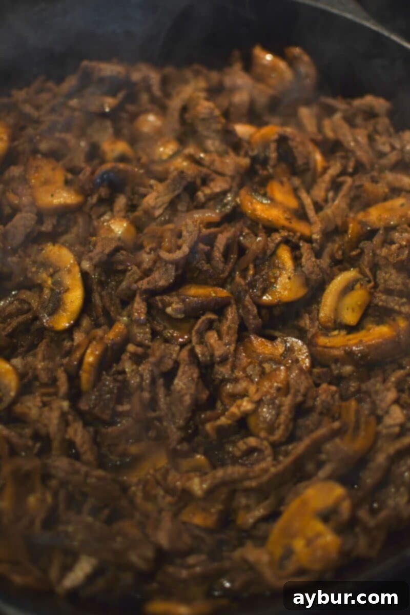 Stuffed Peppers with Philly Cheesesteak 8 A close-up of the fully cooked Philly cheesesteak filling, a mixture of roast beef, onions, and mushrooms, perfectly combined and ready to stuff the bell peppers.