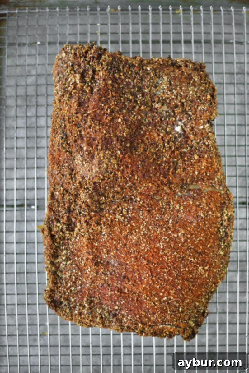 A beautifully roasted and cooled corned beef brisket, seasoned with the homemade pastrami rub, after its first slow cook.