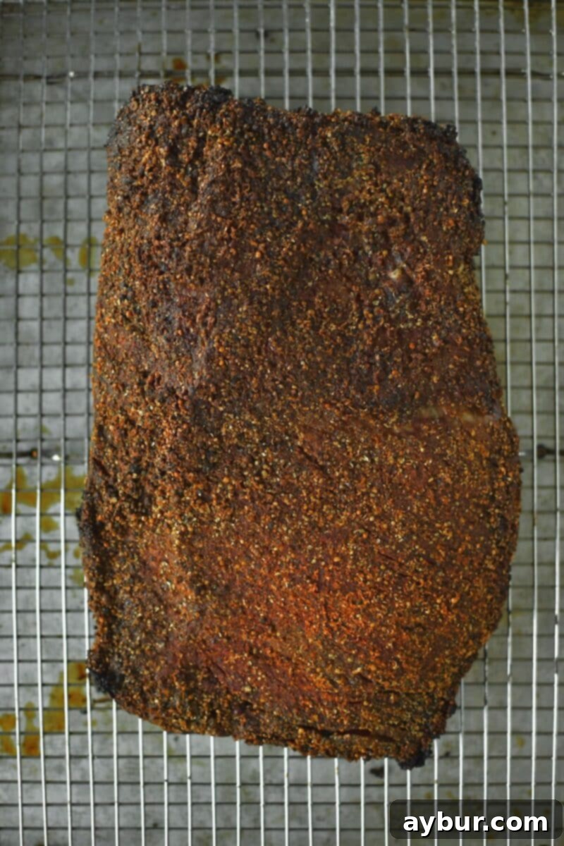 The pastrami after its second bake, showcasing a perfectly set and darkened crust.