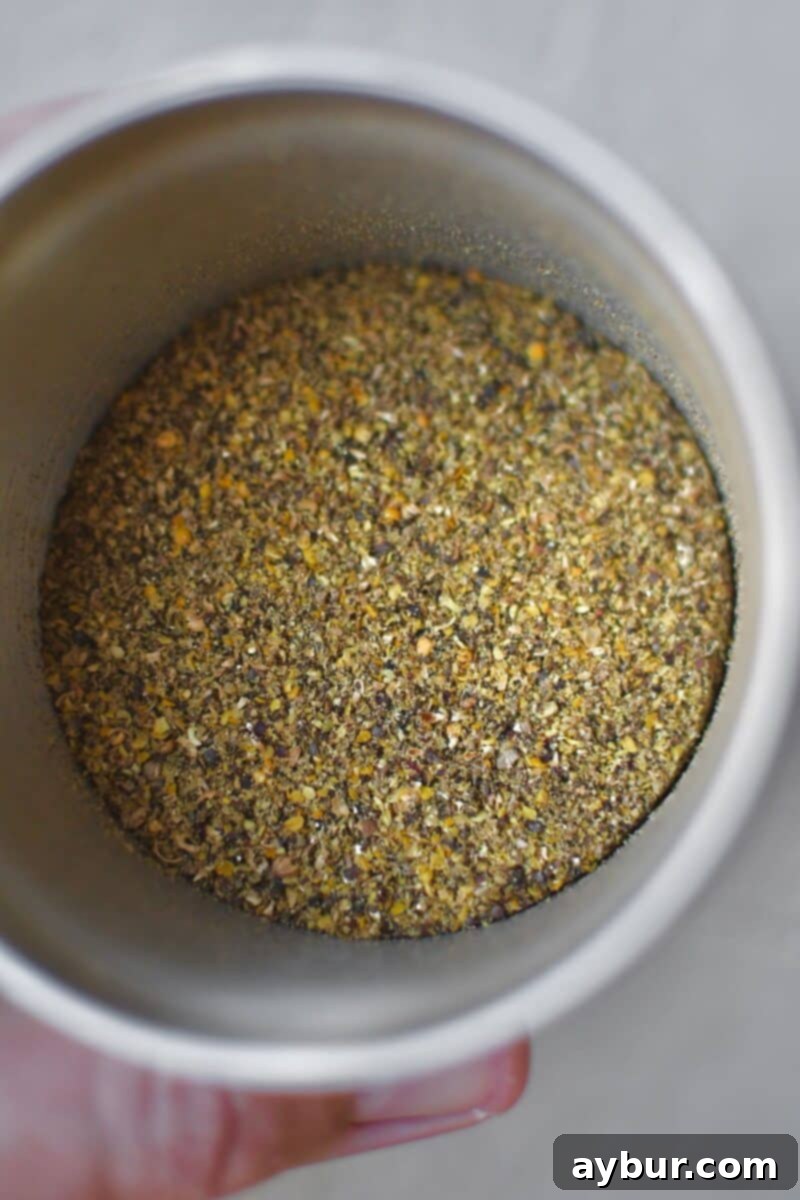 The coarsely ground peppercorns and seeds, showing the ideal cracked texture after pulsing in a spice grinder.