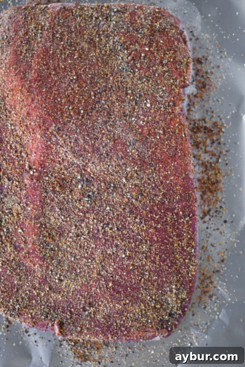A corned beef brisket fully coated in a thick, even layer of homemade pastrami rub.