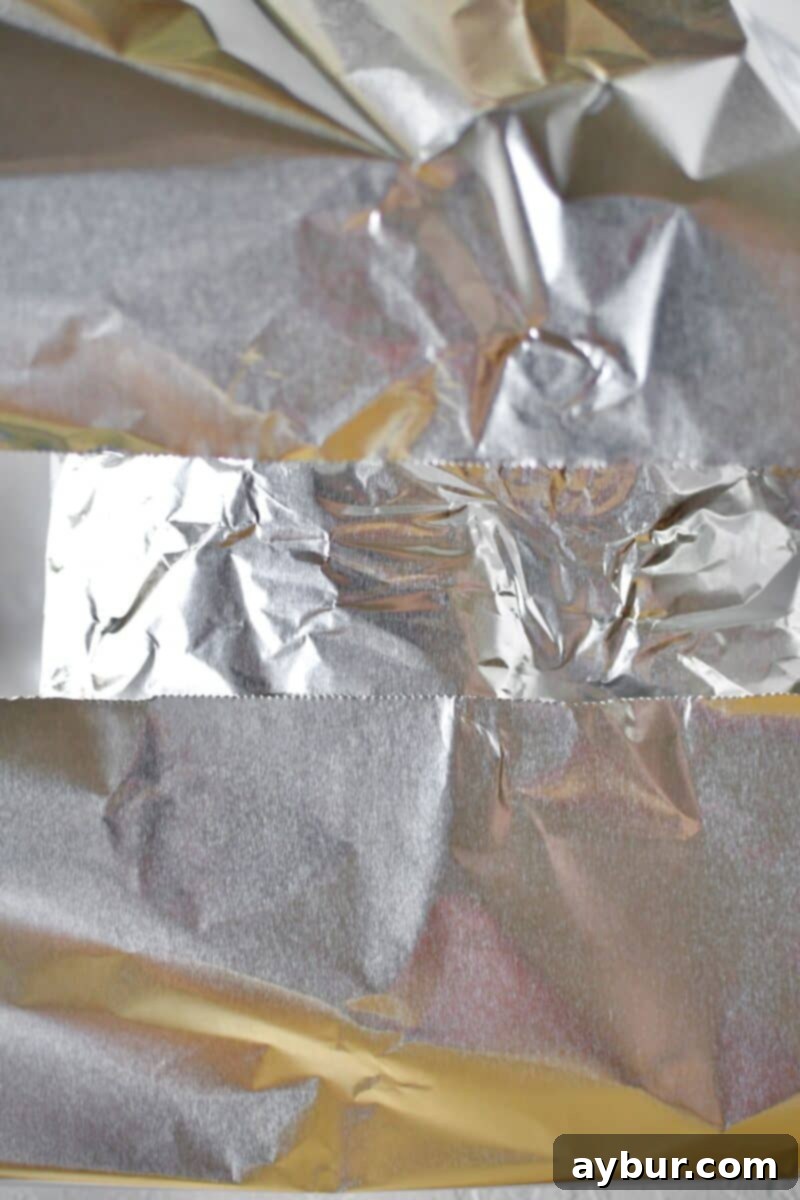 Applying the second layer of tin foil to fully enclose the seasoned corned beef for roasting.