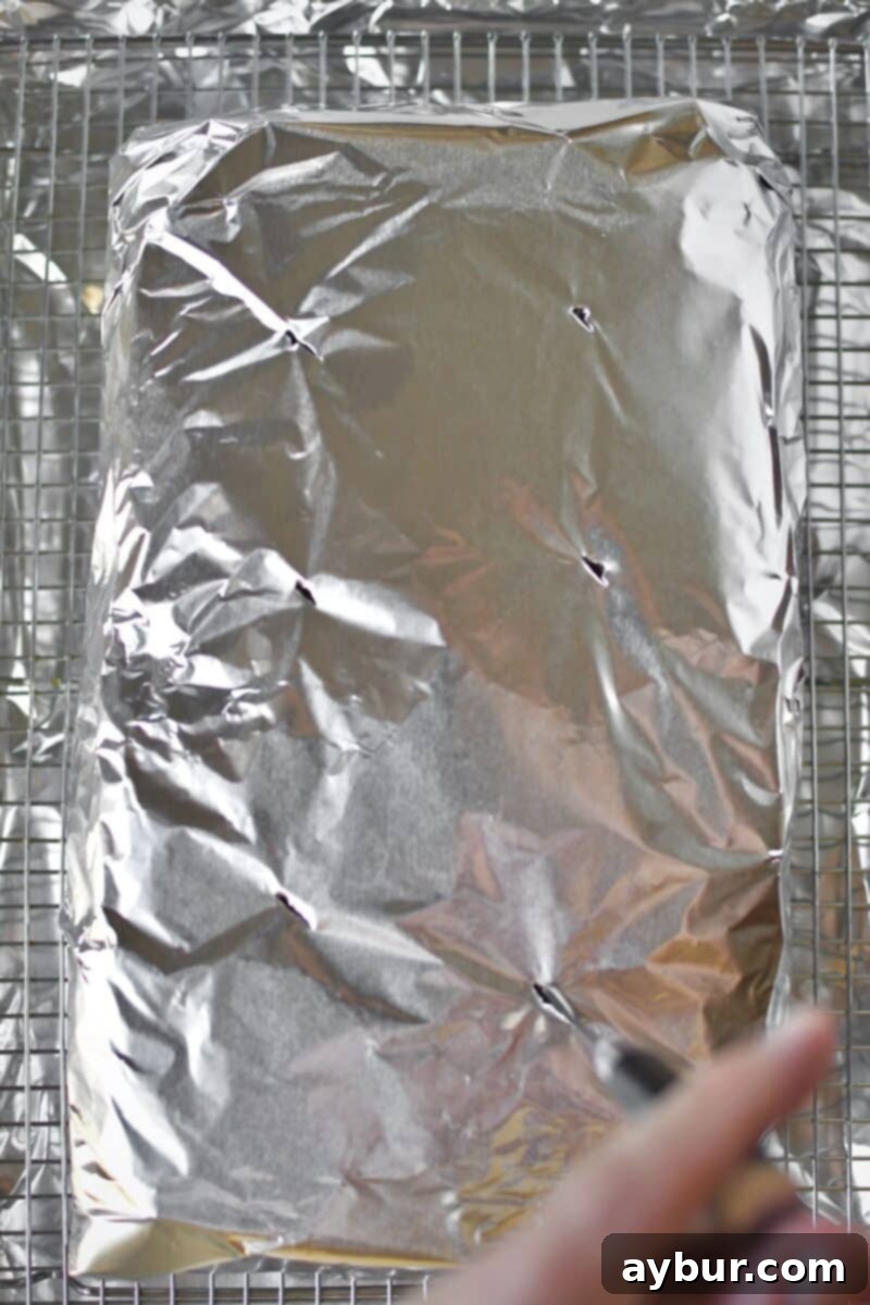 Poking several small holes into the bottom of the foil-wrapped brisket to allow juices to release during cooking.